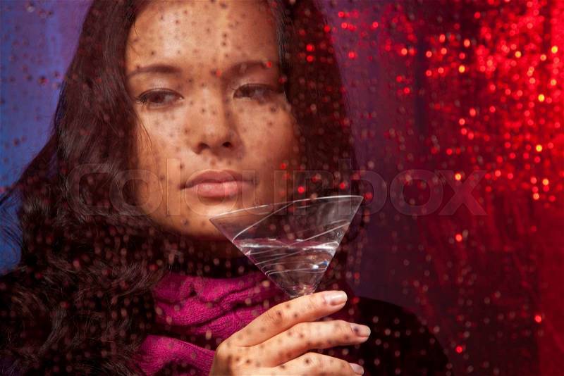 Sad Asian woman with drink in cold rainy weather behind the glass, stock photo