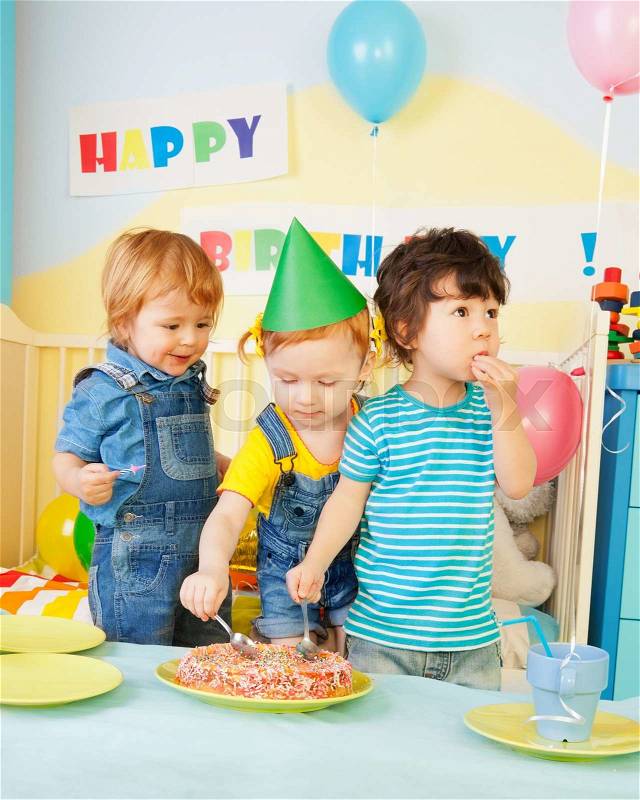 Three kids eating cake on the birthday party- two boys and one girl, stock photo