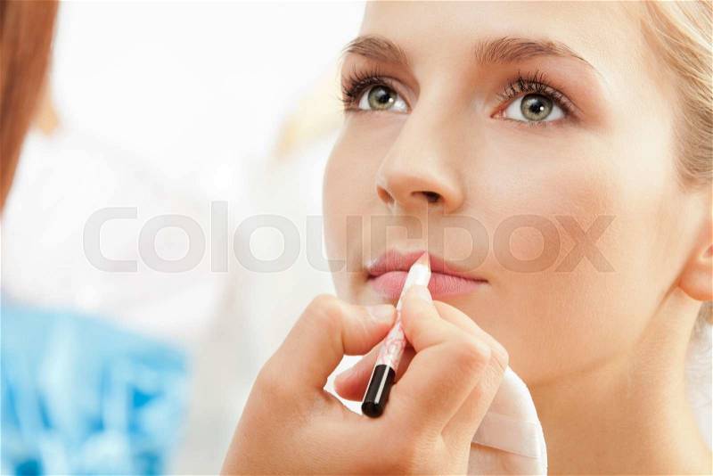 Close-up of makeup artist work - defining lips shape with lip pencil, stock photo