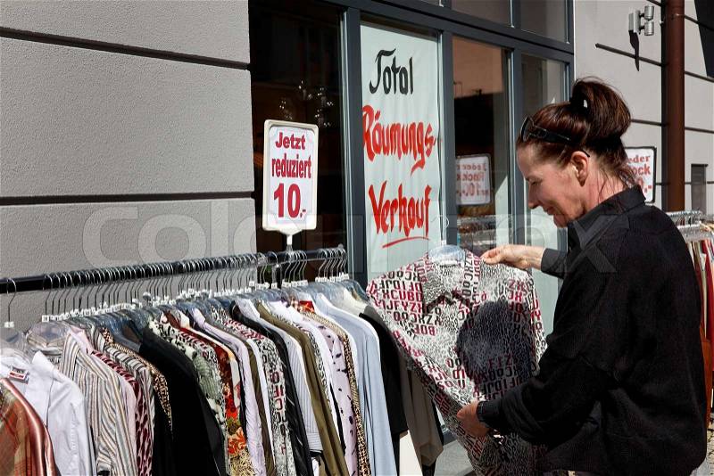 Young woman in front of a special offer on purchase of blouses, stock photo
