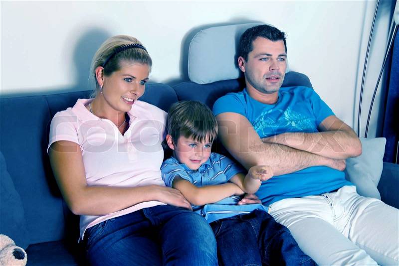 A family watching TV with child on the evening, stock photo