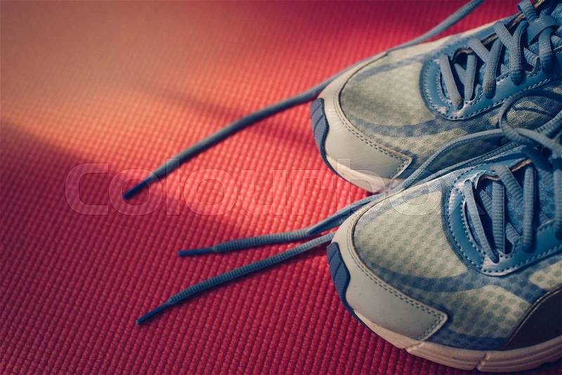 Close up blue sport shoes on pink yoga mat with nature light in the morning, stock photo