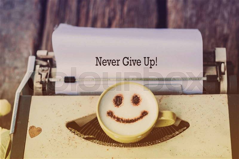 Typewriter with coffee cup, sepia tone. Message Never give up, stock photo