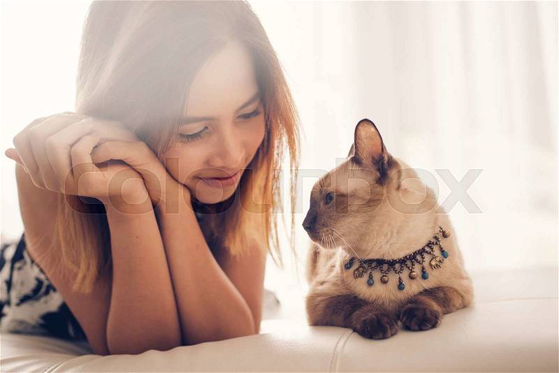 Asian woman and cat laying on sofa with window light, stock photo