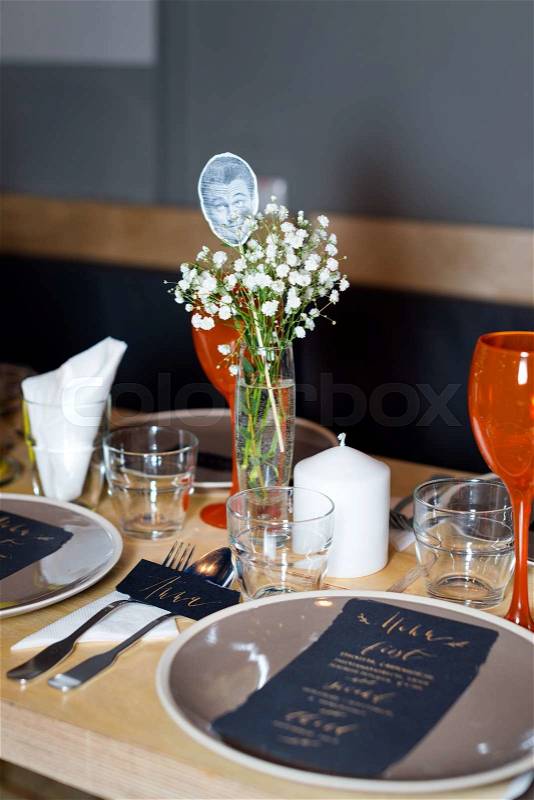 Decorated table ready for dinner. Beautifully decorated table set with flowers, candles, plates and serviettes for wedding or another event in the restaurant, stock photo
