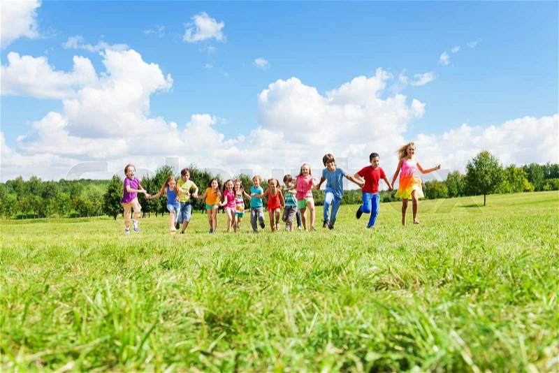 Large group of happy smiling kids, boys and girls running in the park on sunny summer day in casual clothes, stock photo