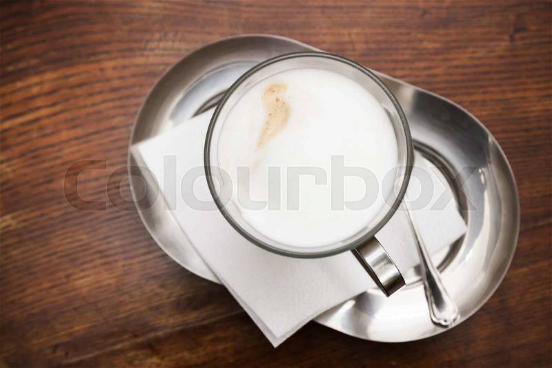 Cappuccino. Cup of coffee with milk foam stands on wooden table in cafeteria, top view, stock photo