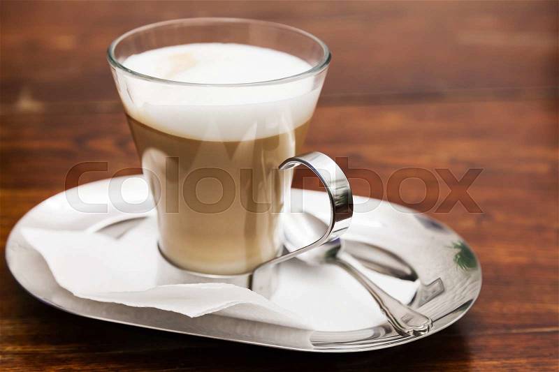 Cappuccino. Cup of coffee with milk foam stands on wooden table in cafeteria, stock photo