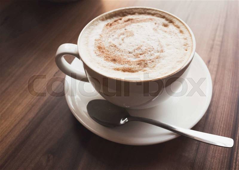 Cappuccino. Cup of coffee with milk foam stands on wooden table in cafeteria, vintage tonal correction photo filter, old style effect, stock photo