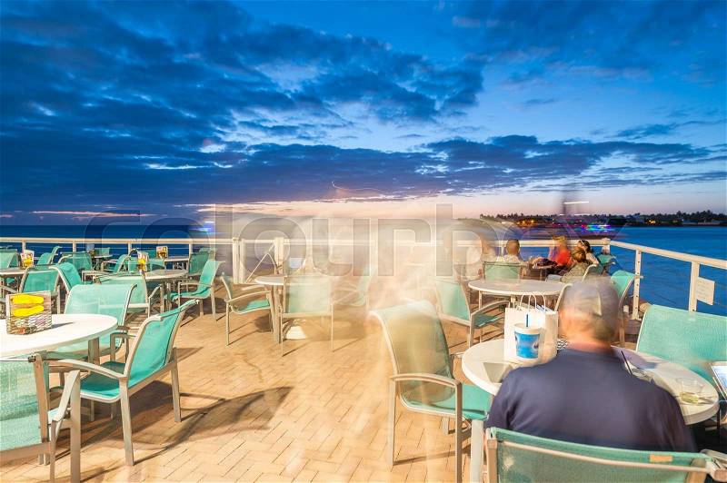 People relaxing in open air restaurant in front of the sea at sunset time, stock photo
