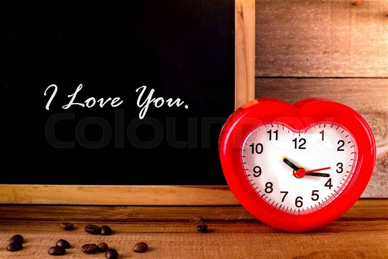 Red alarm clock with heart shape and blakc board with message I love you. Valentine concept, stock photo