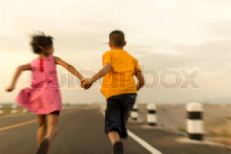 Back of children holding hand and running on the road during sun set, stock photo
