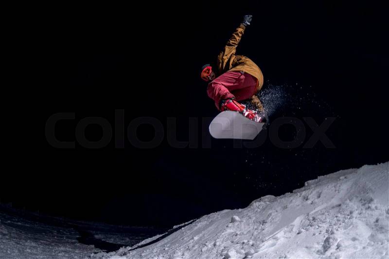 Snowboarder jumping at night, stock photo