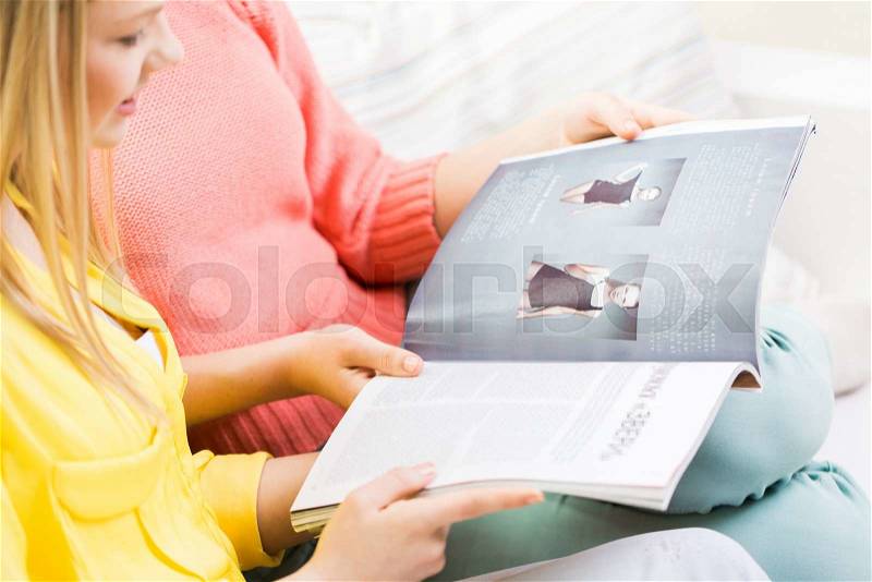 People, mass media, fashion and friendship concept - close up of happy teenage girls reading magazine, stock photo