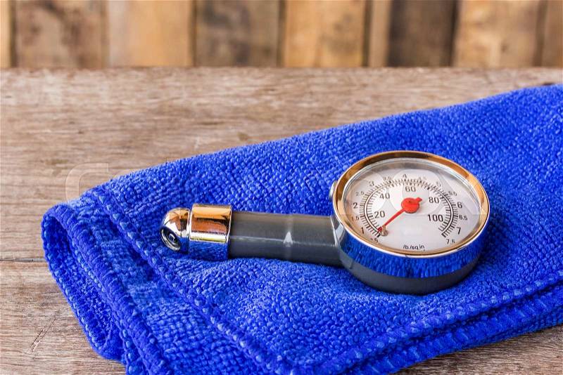 Tire pressure gauge and microfiber cloth on wooden table background, stock photo