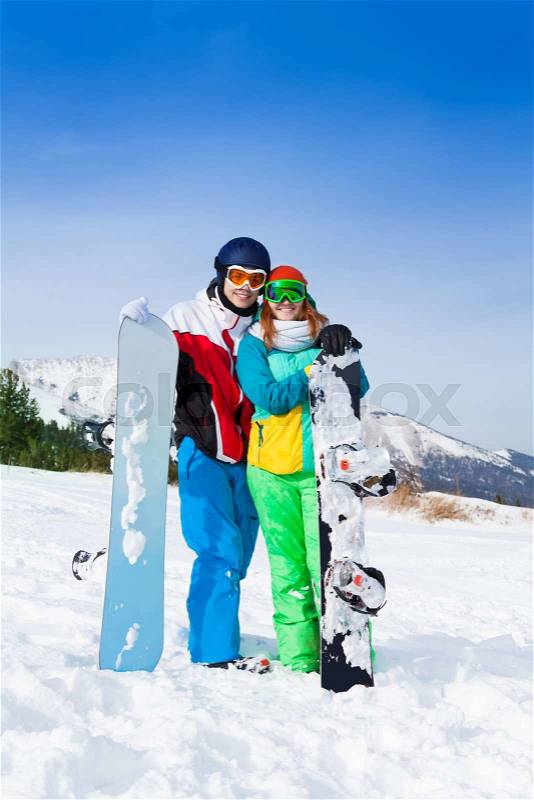 Smiling couple in ski masks standing together on the snow in ski resort, stock photo