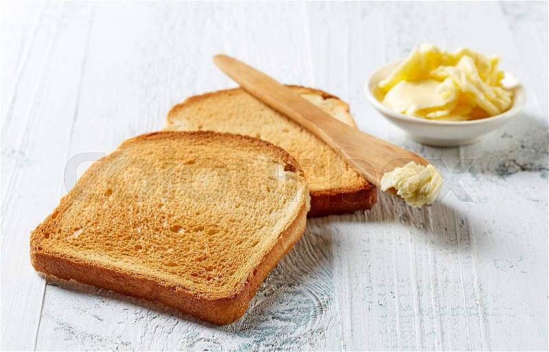 Slices of toast bread and butter on wooden table, stock photo