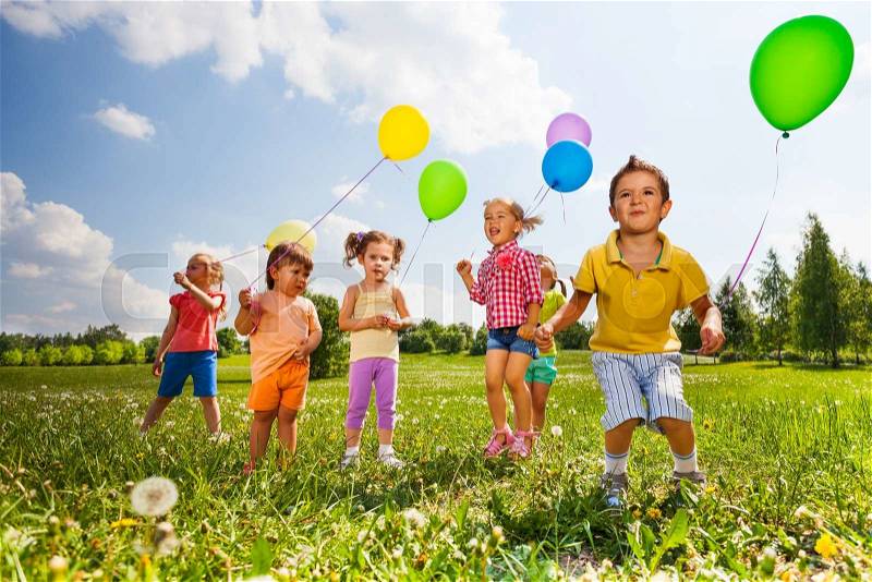 Children with colorful balloons running in field in summer, stock photo