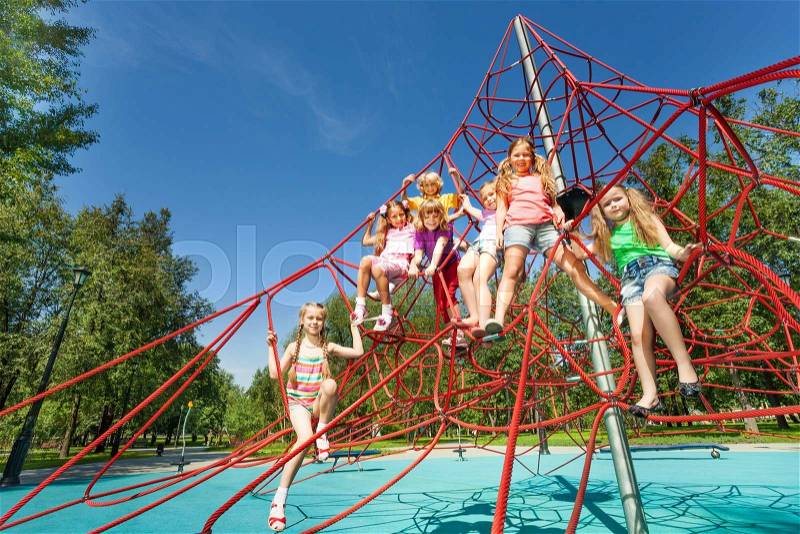 Large group of playful kids sit on red ropes of playground and play together, stock photo