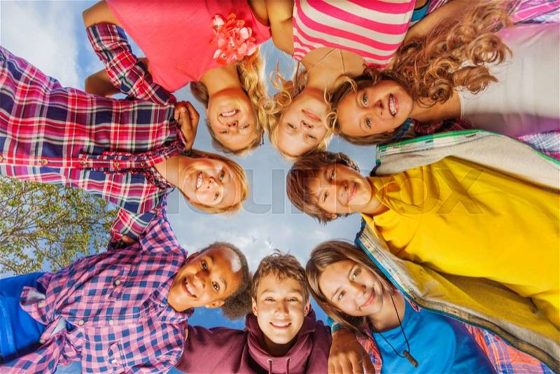 Below view of children standing in circle form on sky background during summer sunny day, stock photo