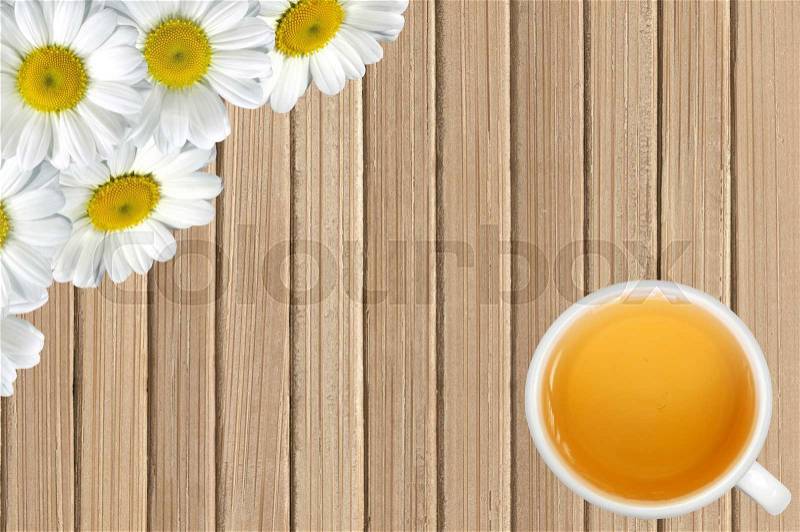 White chamomile flowers and tea cup on wooden table background, stock photo