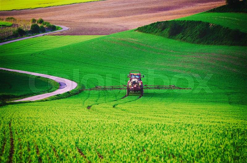 Farm machinery spraying insecticide to the green field, agricultural natural seasonal spring background, vintag retro hipster style, stock photo