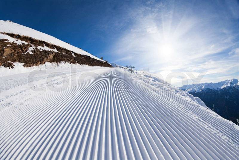 Sunny winter landscape of snow ski-track and Caucasus mountains during day in Sochi ski resort Krasnaya polyana, Russia, stock photo