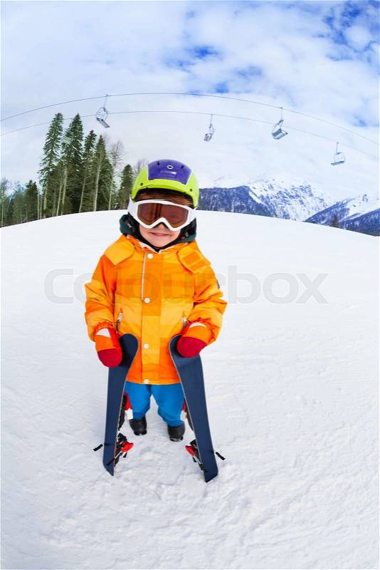 Cute boy wearing ski mask and helmet stands on Sochi ski resort Krasnaya polyana in Russia, stock photo