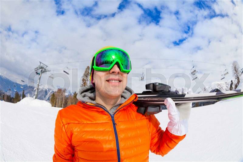 Smiling young man wearing ski mask holds ski with beautiful mountain view on Sochi ski resort Krasnaya polyana in Russia, stock photo