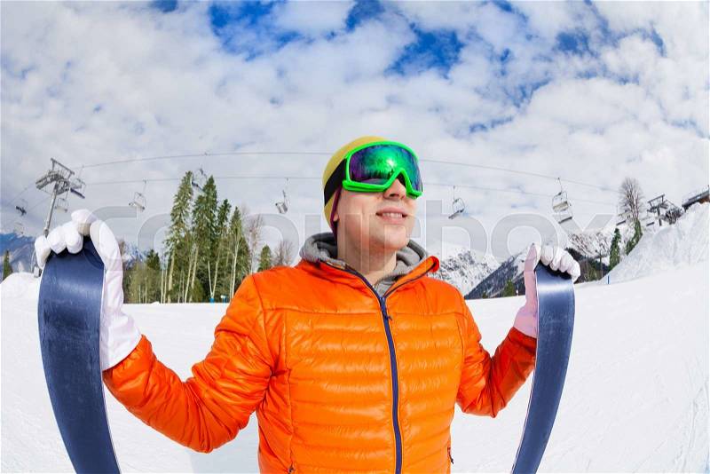 Smiling guy wearing ski mask holds ski with beautiful mountain view on Sochi ski resort Krasnaya polyana in Russia, stock photo