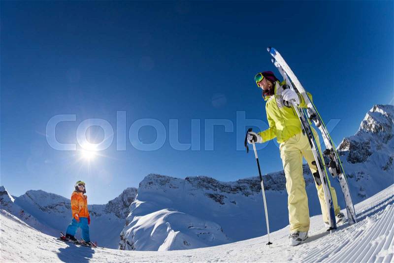 Small boy and woman in mask standing and holding ski and ski poles during sunny winter day on Krasnaya polyana ski resort and Caucasus mountains in Sochi, Russia, stock photo