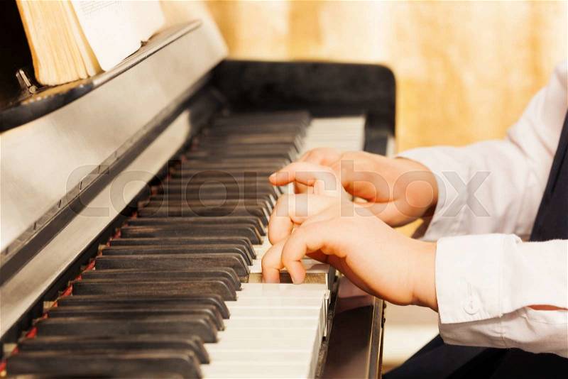 Child\'s hands playing on the piano-keys close-up view, stock photo