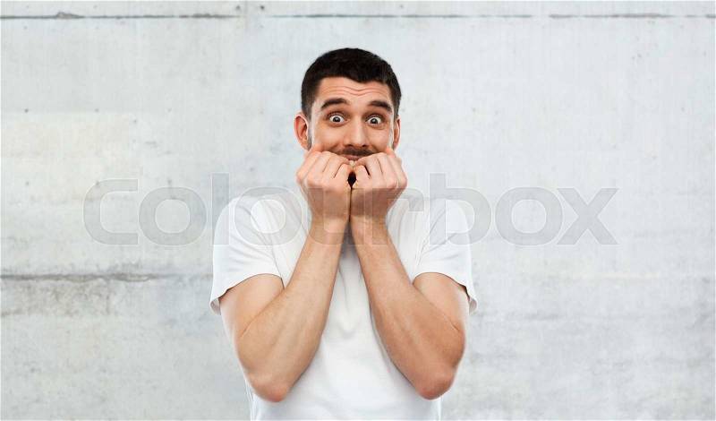 Emotion, advertisement and people concept - scared man in white t-shirt over gray wall background, stock photo