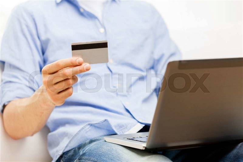 Technology, people and online shopping concept - close up of man with laptop computer and credit card at home, stock photo