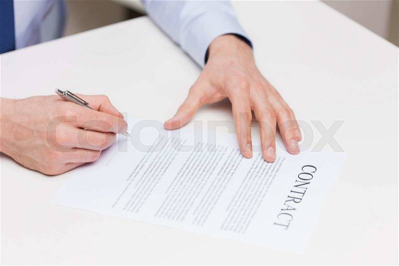 People, business and paperwork concept - close up of male hands signing contract document at office, stock photo