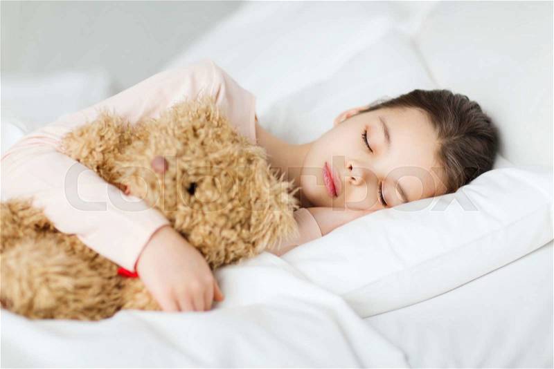 People, childhood, rest and comfort concept - girl sleeping with teddy bear toy in bed at home, stock photo