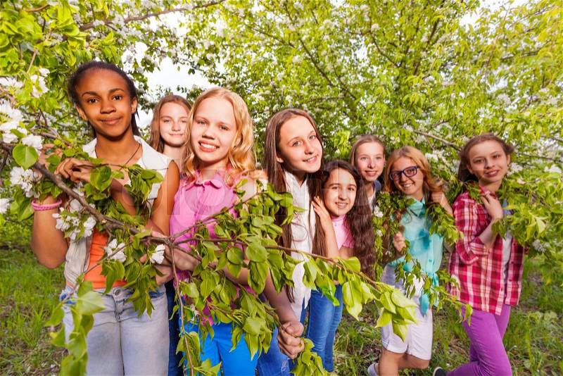 Group of teen age girls in the spring apple garden posing together, stock photo