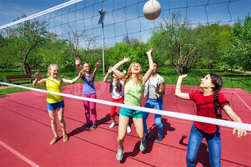View through volleyball net on game of girls playing on the playground during summer sunny day, stock photo
