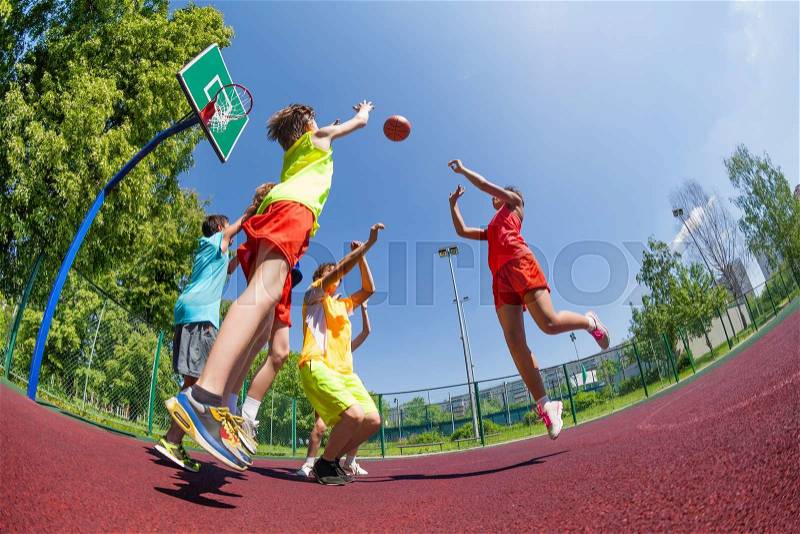 Fisheye view of teenagers playing basketball game together on the playground during sunny summer day, stock photo