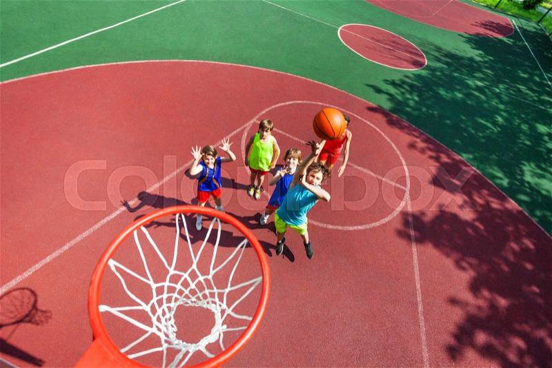 Kids standing on ground down and ball flying to the basket from top during basketball game, stock photo