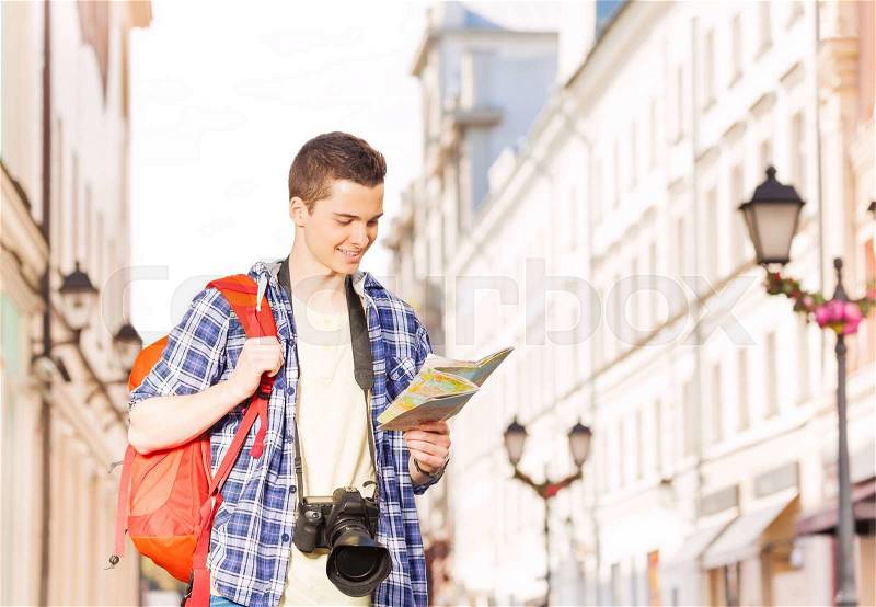 Boy with camera and city map on the street during summer vacation time in Europe, stock photo