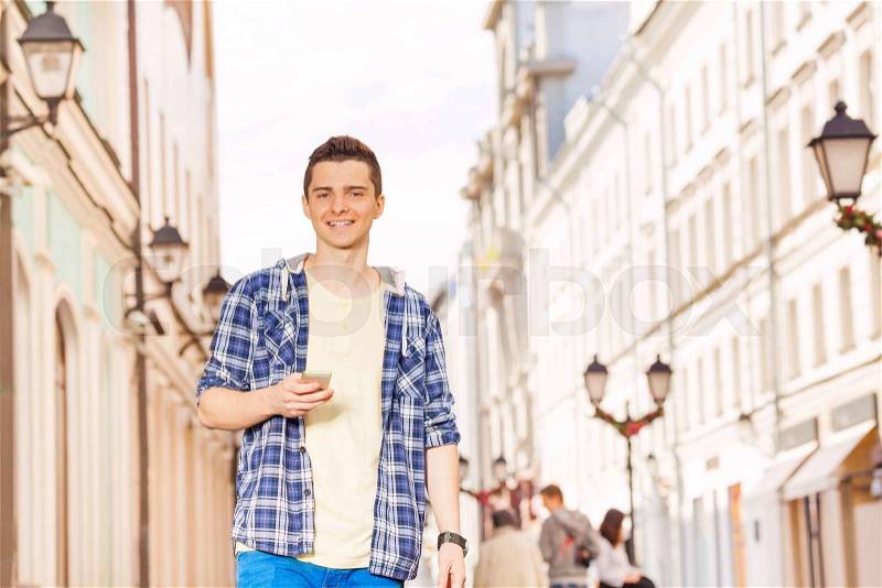 Young man with mobile phone on the street during summer vacation time in Europe, stock photo