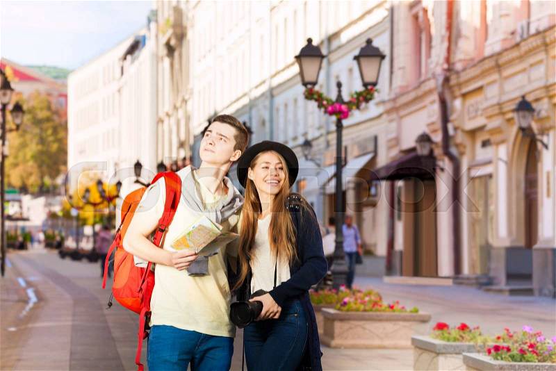 Beautiful young woman and man as tourists sightseeing on the European street during summer day time, stock photo