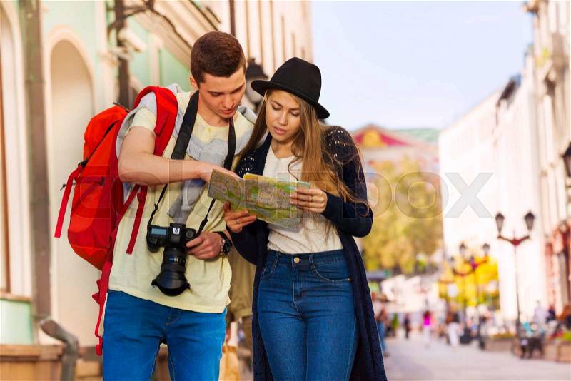 Young man and girl as tourists hold city map on the European street during summer day time, stock photo