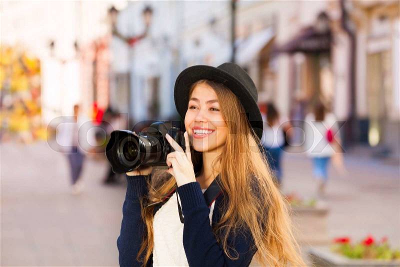 Beautiful young woman in retro outfit shooting with camera touristic attractions on the European street during summer day time, stock photo
