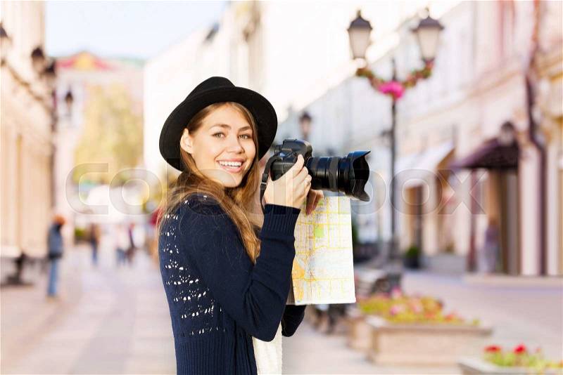 Smiling young woman shooting with camera touristic attractions on the European street during summer day time, stock photo