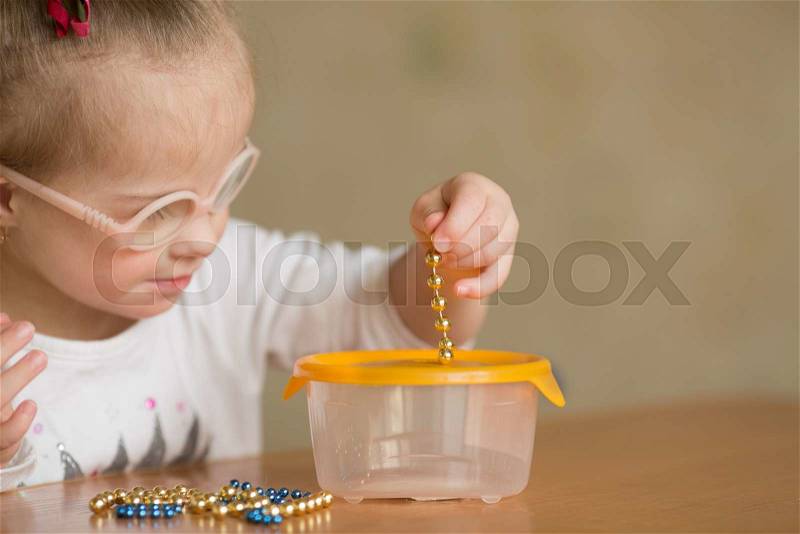 Girl with Down syndrome develops fine motor skills of hands, stock photo