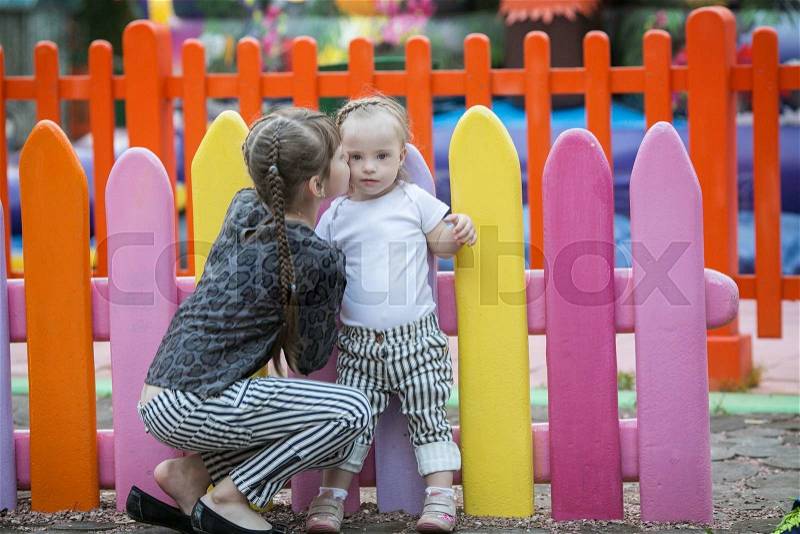 Older sister kissing a beautiful girl with Down syndrome, stock photo