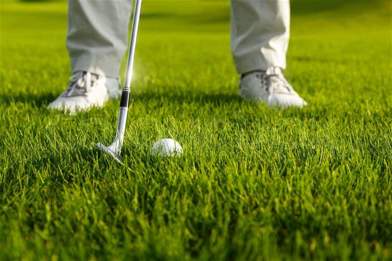 Golf ball and golf club in front of golf player, stock photo