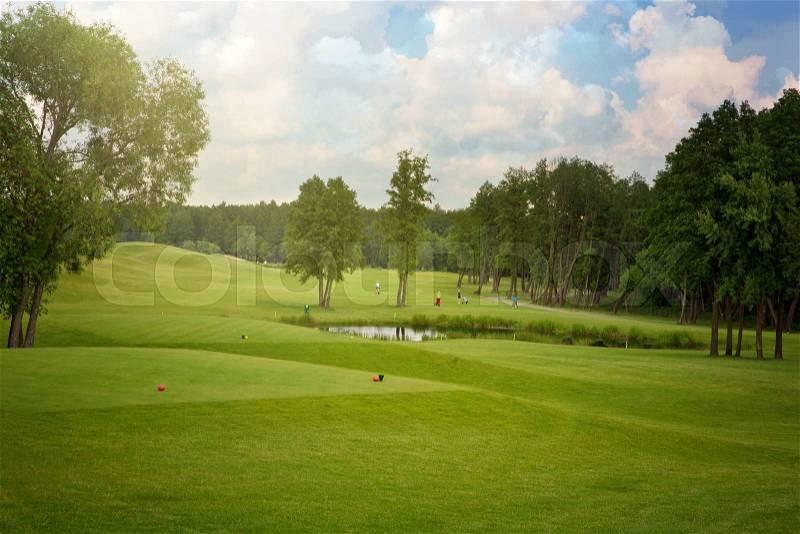 Golf field with trees over cloudy blue sky, stock photo